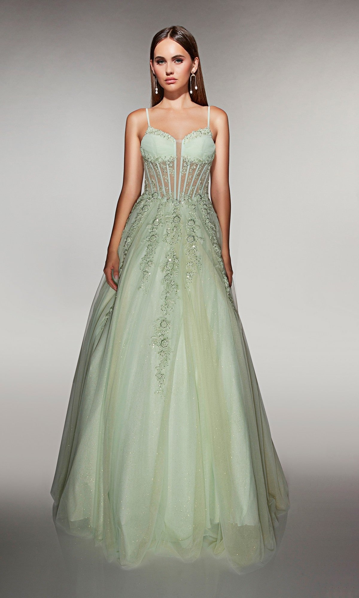 A woman wears the Alyce 62061 long prom dress in mint, featuring a sleeveless lace corset bodice and a flowing tulle ballgown skirt with floral embellishments.